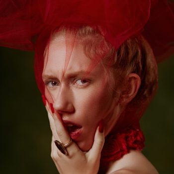 Fine art fashion portrait of woman wearing red tulle over her head